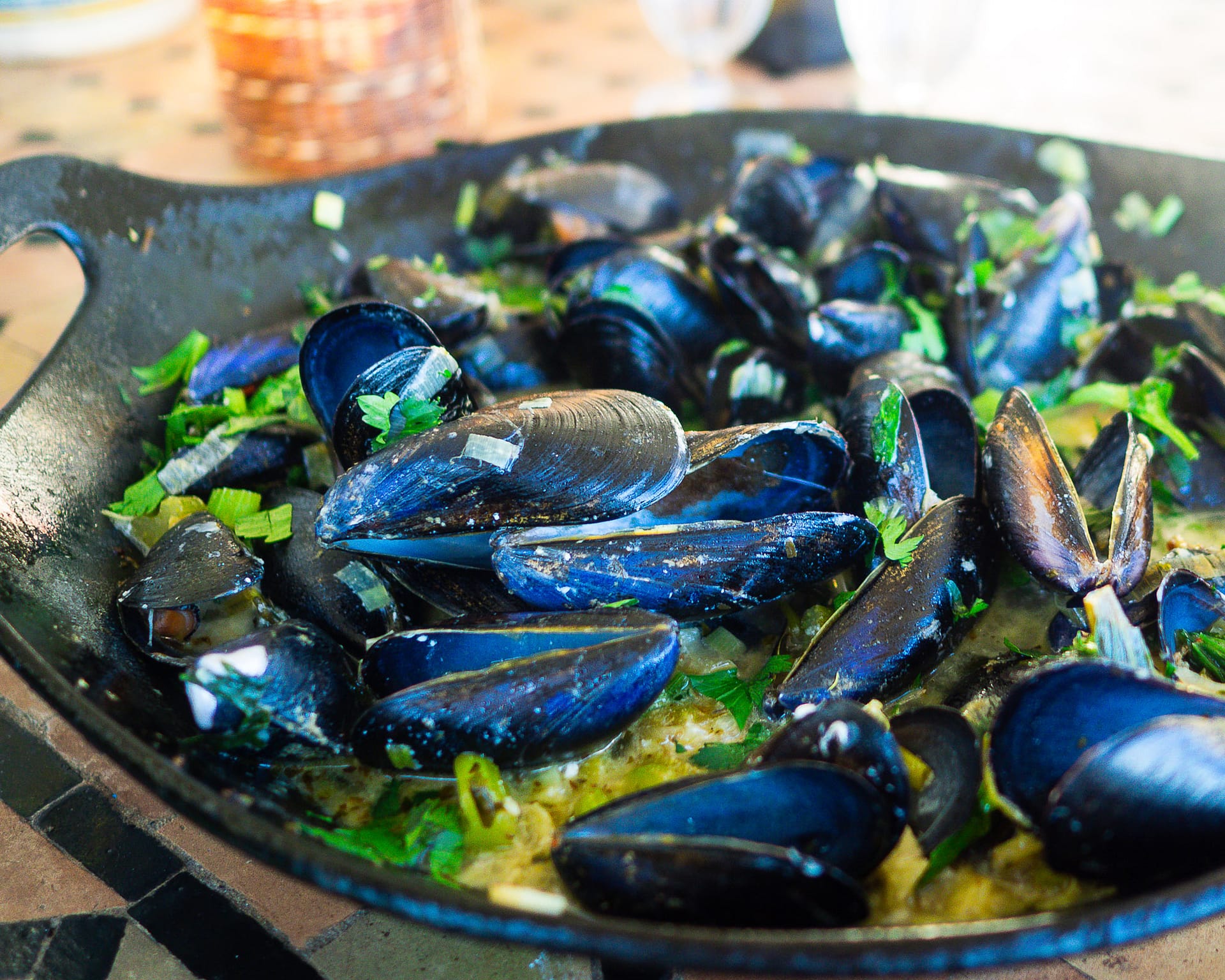 The finished dish of Mussels Infused in Garlic and Wine in a heavy black bowl.