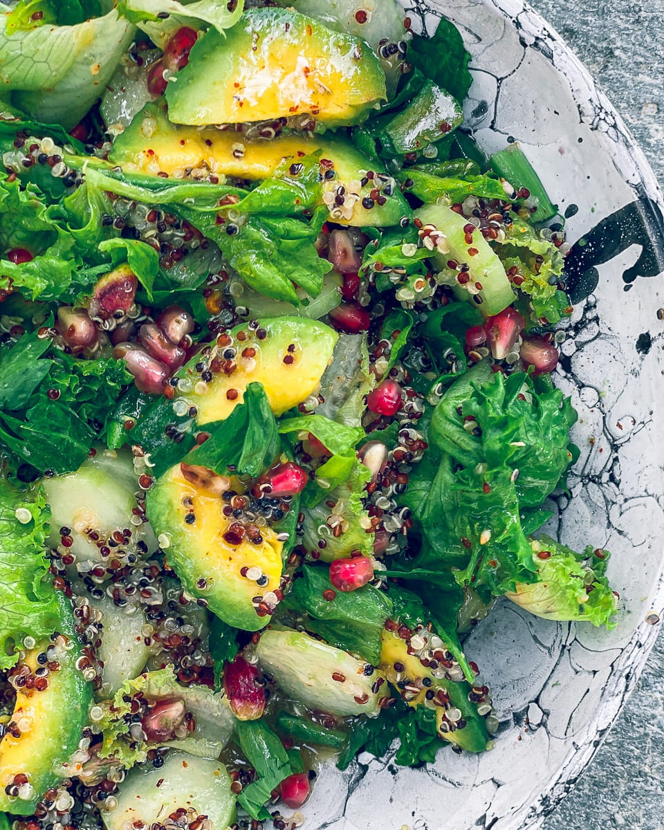 Salad bowl with quinoa, avocados, cucumber, lettuce and pomegranate seeds coated in a za'atar spiced dressing