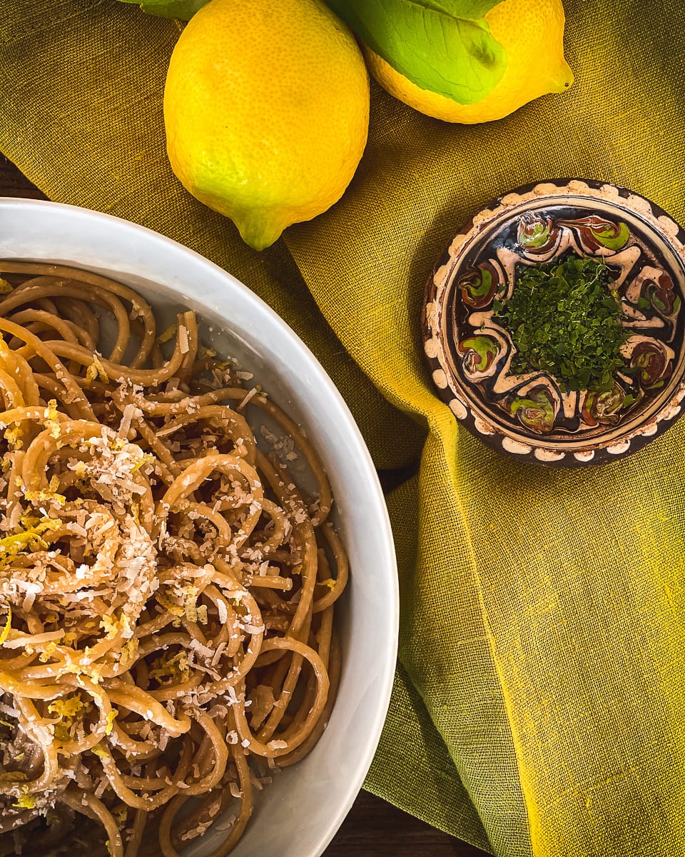 Bowl of Pasta al Limone with fresh lemons and dried lemon leaf garnish