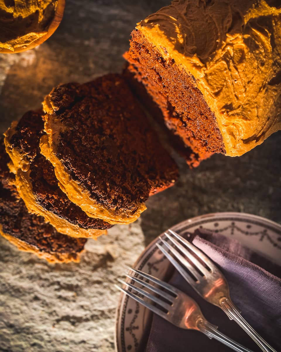 Dark brow ginger loaf cake, with ginger coloured icing on stone background.