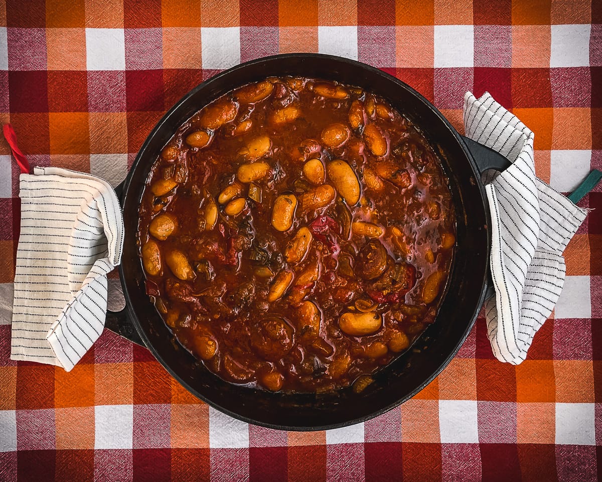 Cast iron casserole dish with Chorizo and Bean Stew in a dark red tomato sauce.
