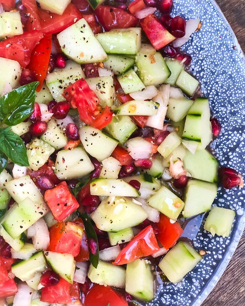 Tomato and cucumber salad with pomegranate seeds, chillies, with chopped mint, lemon and basil.