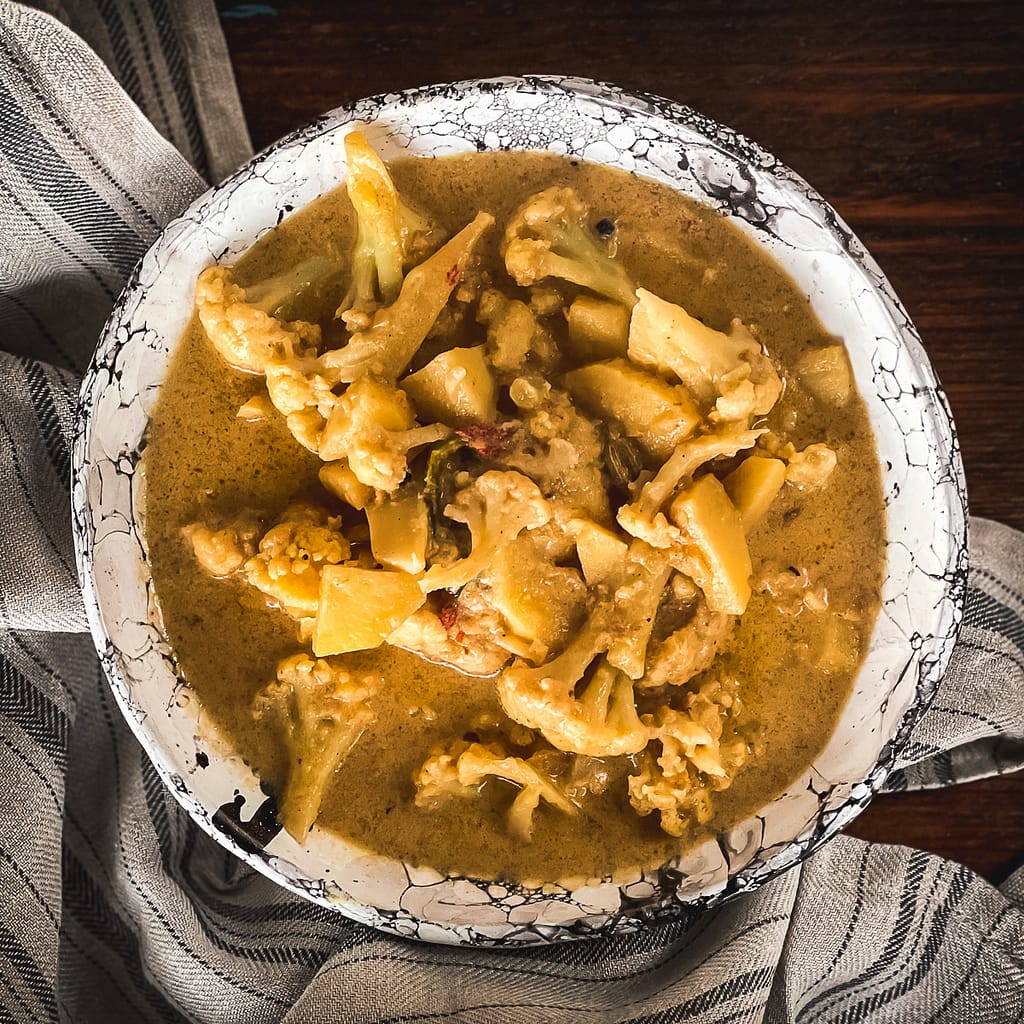 Cauliflower in a creamy aromatic sauce in a handmade black and white bowl.
