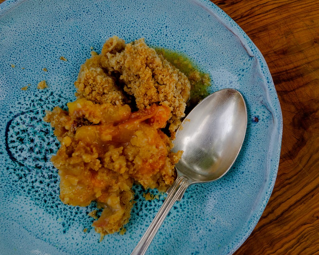 Classic Crumble with Apricots ready to serve on a blue plate