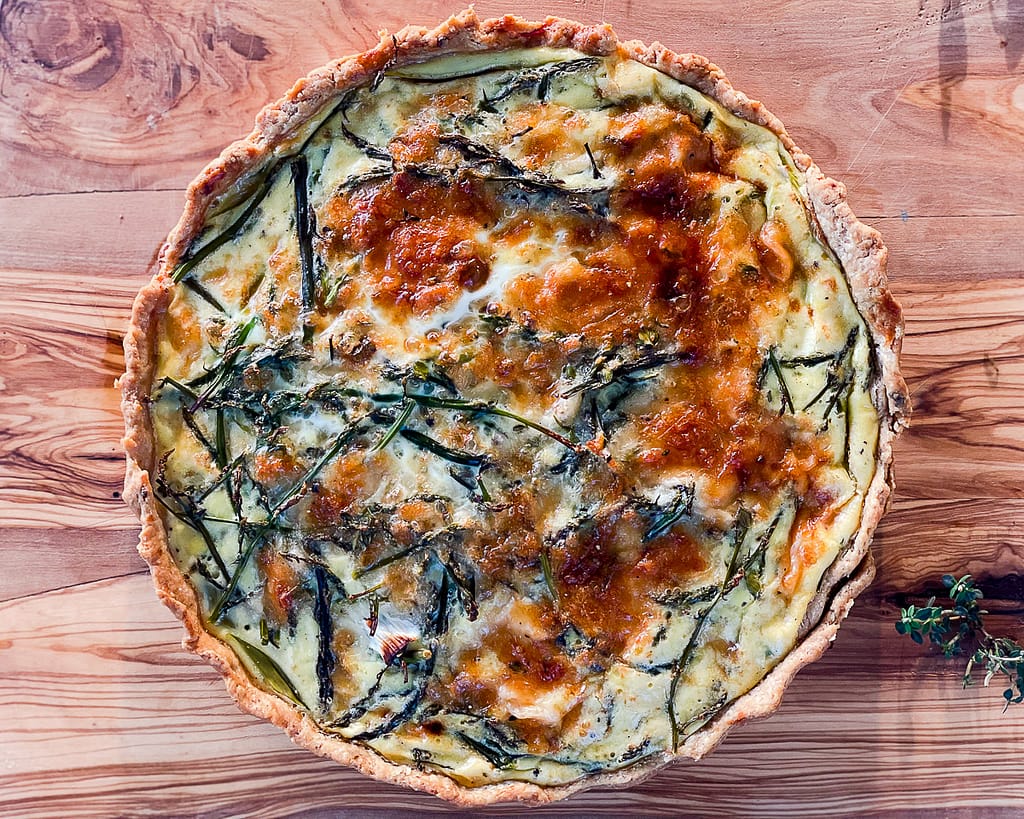 Wild asparagus quiche served on a olive wood platter.