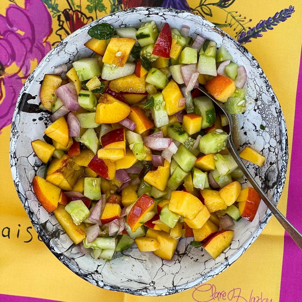 Summer salad with nectarines on a colourful tablecloth.