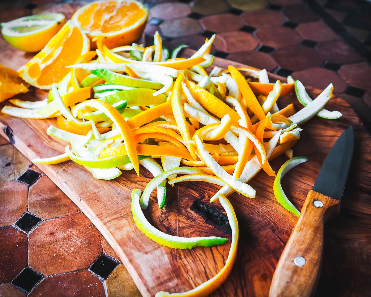Citrus fruit on a chopping board being prepared for candied peel