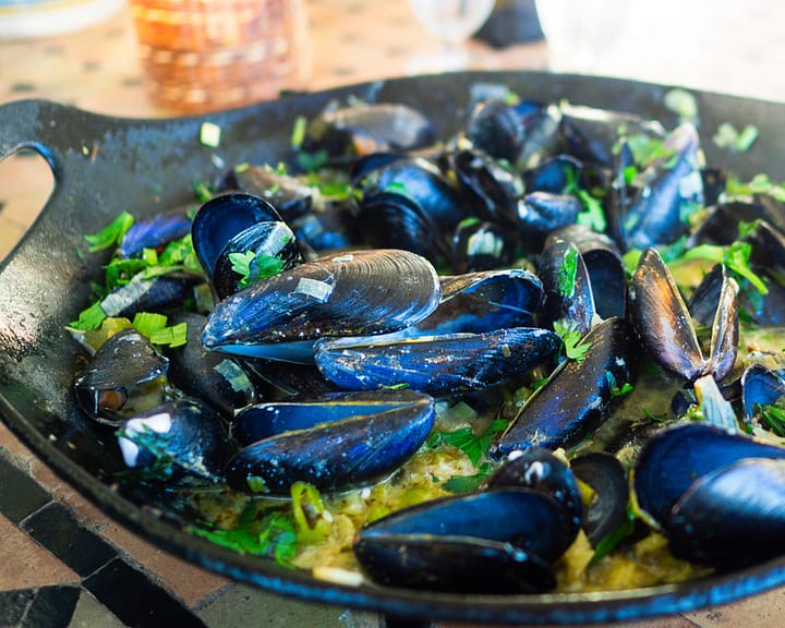 The finished dish of Mussels Infused in Garlic and Wine in a heavy black bowl. 