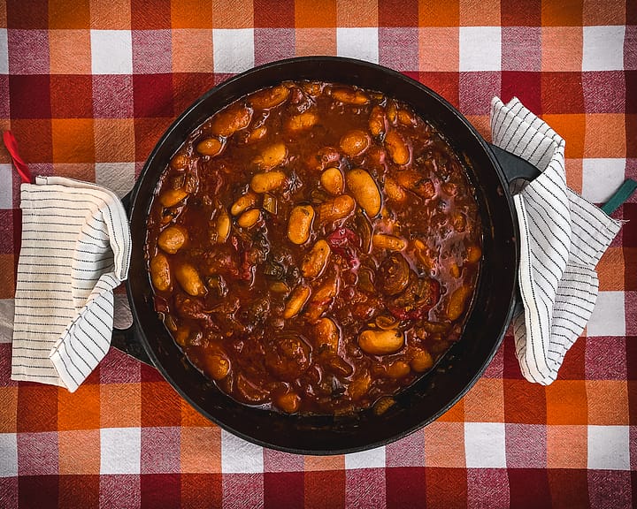 Cast iron casserole dish with Chorizo and Bean Stew in a dark red tomato sauce.