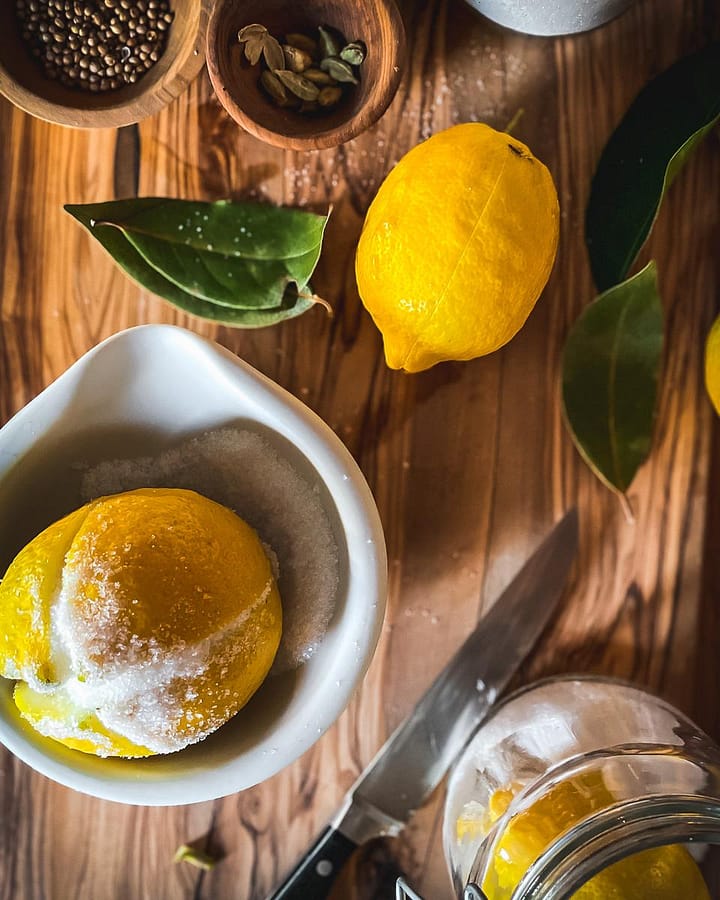 Preparation of a lemon to preserve in salt with bay leaves and spices.