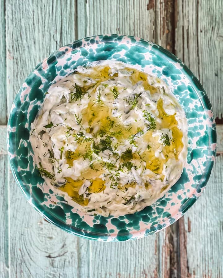 Tzatziki garnished with lemon and olive oil and finely chopped dill