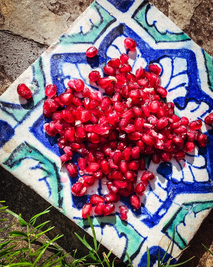 Pomegranate seed piled on top of a Middle Eastern style tile