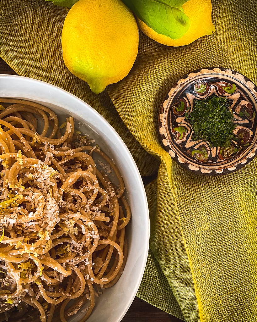 Bowl of Pasta al Limone with fresh lemons and dried lemon leaf garnish