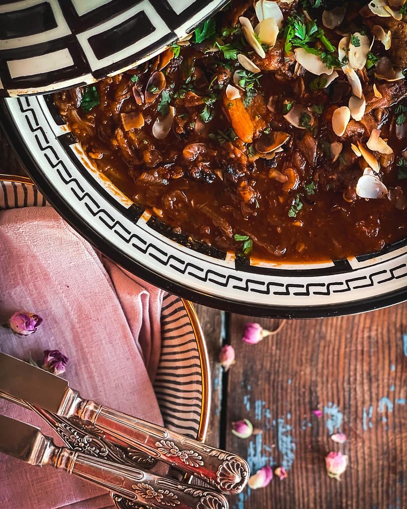 Decorative black and white tagine pot with lamb and apricot tagine in a rich sauce.
