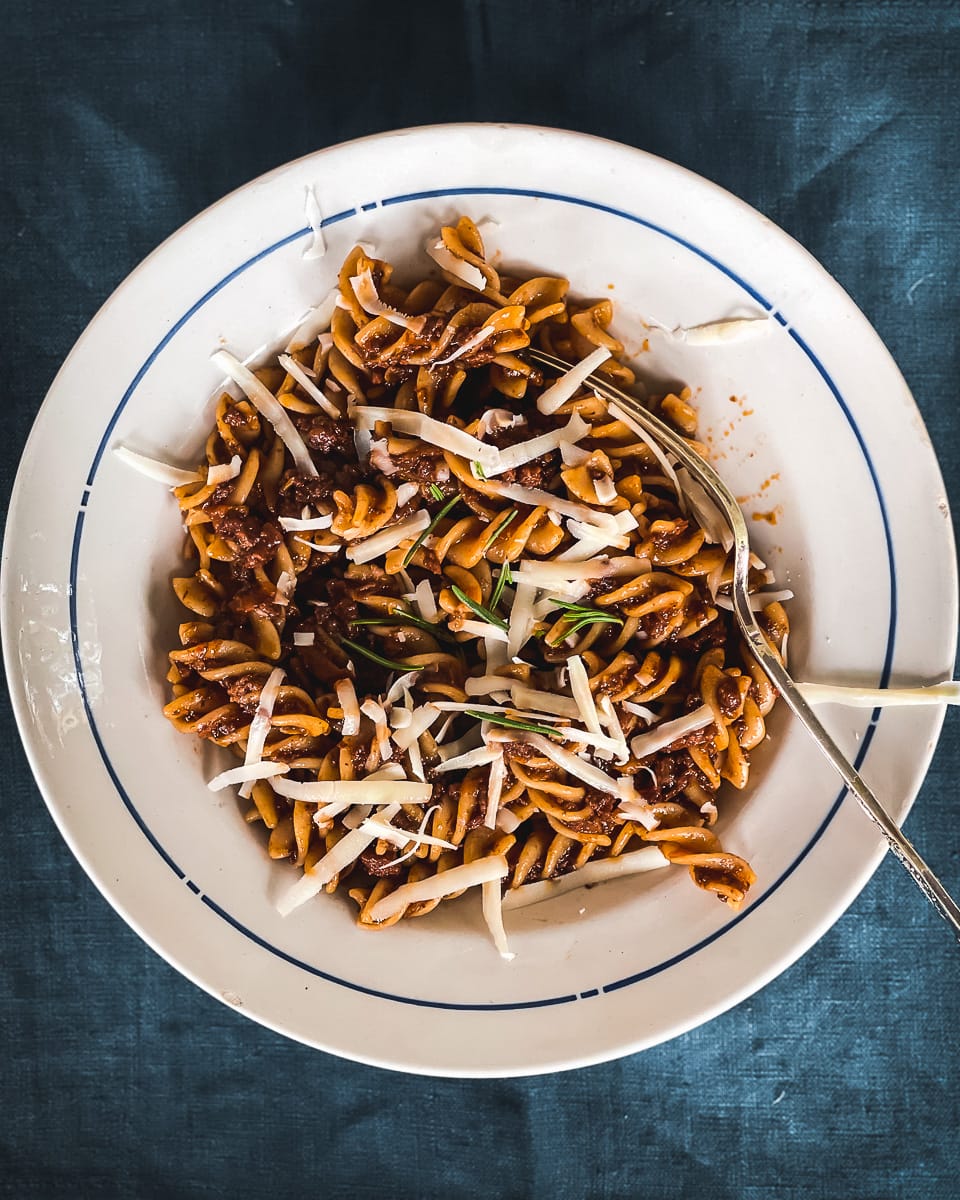 A bowl of fusilli pasta with a meat ragu sauce, rosemary and grated parmesan