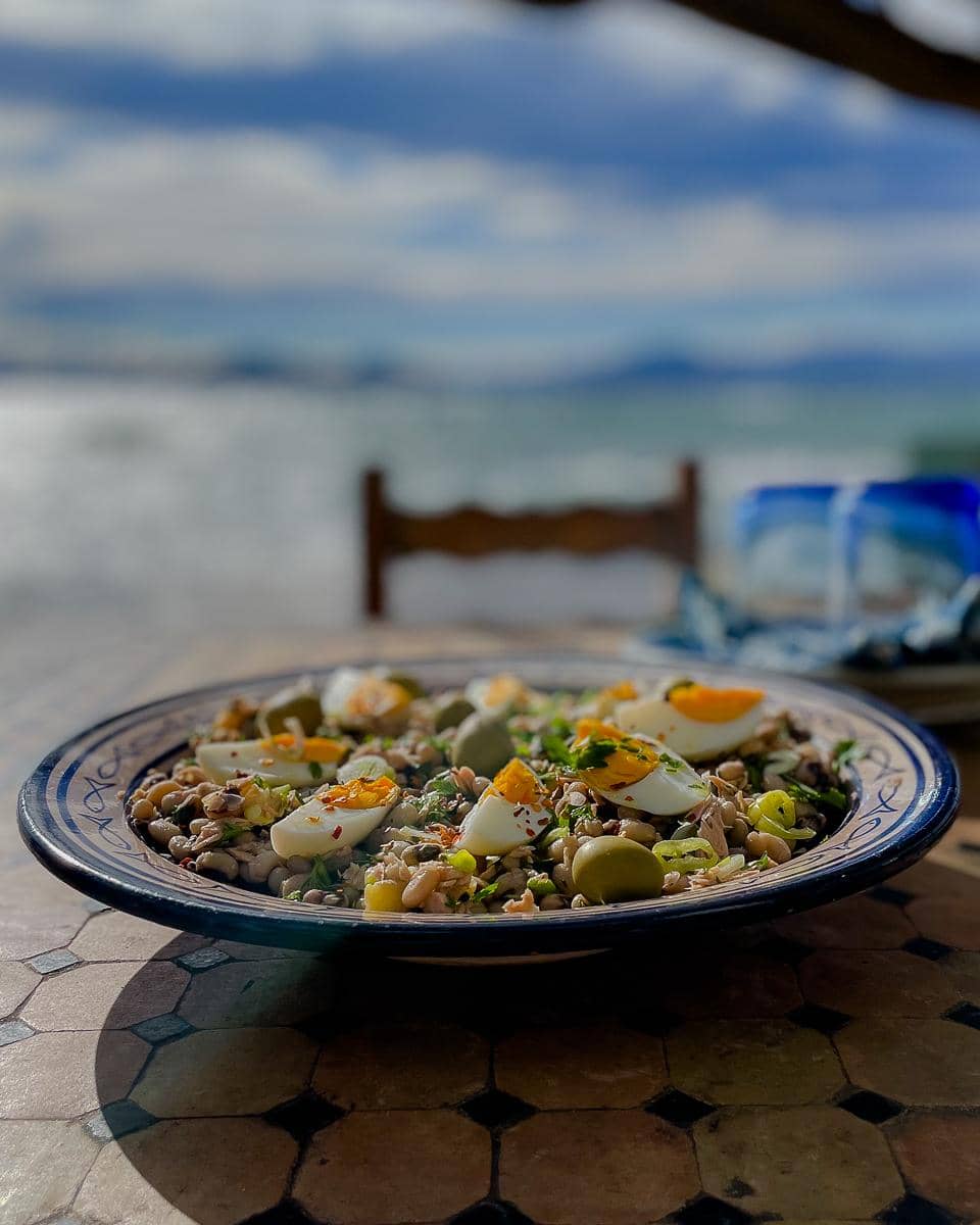 A large salad bowl with black-eyed bean salad looking out to sea.